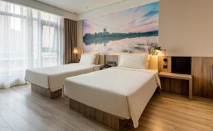 two beds in a hotel room with a painting on the wall at Atour Hotel Xi'an West Erhuan Road Tai'ao in Xi'an