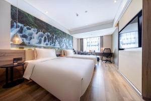 昆明市にあるAtour Hotel Kunming South High Speed ​​Railway Station University Townのベッド2台とテーブルが備わるホテルルームです。