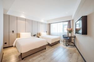 una camera d'albergo con due letti e una televisione di Atour X Hotel Kunming Cultural Palace East Renmin Road a Kunming