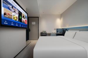 um quarto de hotel com uma cama e uma televisão de ecrã plano em Atour Light Hotel Guangzhou East Fuhua Road Panyu Plaza em Guangzhou