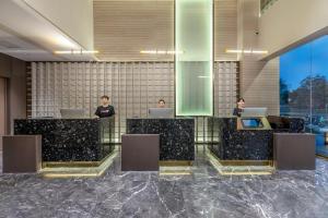 un vestíbulo con 3 personas sentadas en escritorios con ordenadores portátiles en Atour S Hotel Xiamen Cross-Strait Financial Center, en Xiamen