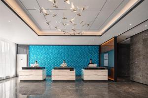 3 personnes assises à la réception dans le hall dans l'établissement Atour Hotel Guangzhou Baiyun New Town Jiangxia Metro Station, à Canton