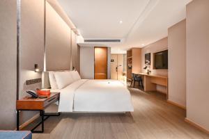 a bedroom with a large white bed and a desk at Atour Hotel Beijing Lishuiqiao in Changping