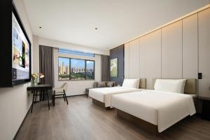 a hotel room with two beds and a television at Atour Hotel Huizhou Huiyang New Metropolis in Huizhou