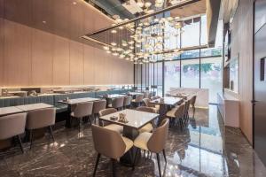 Atour Hotel Shenzhen Futian CBD Civic Center في شنجن: مطعم بطاولات وكراسي وثريا