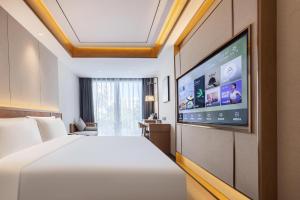 a hotel room with a bed and a flat screen tv at Atour X Hotel Beijing Haidian Sijiqing in Beijing
