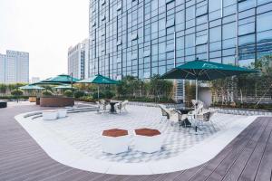 un patio con tavoli, sedie e ombrelloni di Atour S Hotel Hangzhou Binjiang Olympic Sports a Hangzhou