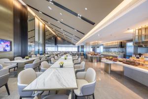 広州市にあるAtour Hotel Guangzhou Zhujiang New Town Taikoo Huiの白いテーブルと白い椅子が備わるレストラン