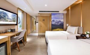 Pokój hotelowy z 2 łóżkami, biurkiem i telewizorem w obiekcie Atour Hotel Chengdu Jinli Hongpailou Subway Station w mieście Chengdu