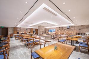 un restaurant vide avec des tables et des chaises en bois dans l'établissement Atour X Hotel Beijing Yonghe Temple Hepingli, à Pékin