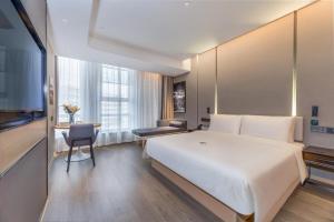 um quarto de hotel com uma grande cama branca e uma secretária em Atour Hotel Zhijiang Bridge em Hangzhou