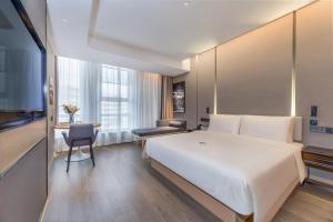 杭州市にあるAtour Hotel Zhijiang Bridgeの大きな白いベッドと机があるホテルの部屋
