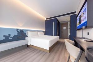 a bedroom with a bed and a desk and a tv at Atour Light Hotel Guangzhou Pazhou Exhibition Canton Tower Subway Station in Guangzhou