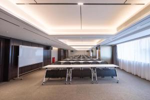 広州市にあるAtour Hotel Guangzhou Zhujiang New Town Taikoo Huiのテーブルと椅子、プロジェクタースクリーンを備えた会議室