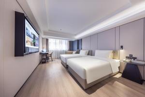 um quarto de hotel com uma cama e uma televisão de ecrã plano em Atour X Hotel Shenzhen Luohu Sungang Baoneng Center em Shenzhen