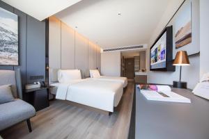 1 dormitorio con 1 cama blanca grande y 1 silla en Atour Hotel Kunming Railway Station Joy City en Kunming