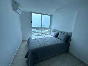 a bed in a room with a large window at Amazing Ocean View 1bed Suite in Panama City