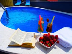 a book and a bowl of fruit next to a swimming pool at Gorgeous homes with swimming pool jacuzzi and a magnificent sea view in Dramalj