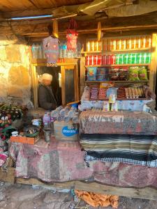 a man sitting inside of a market with a counter with food at Saint Catherine Peak Camp Sunrise Adventure & Church in Saint Catherine
