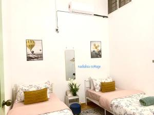 two beds in a room with white walls at Nadialisa cottage homestay For Islamic only in Sungai Petani