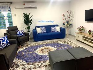 a living room with a blue couch and chairs at Nadialisa cottage homestay For Islamic only in Sungai Petani