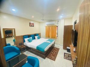 una camera con letto, TV e sedie blu di The Ginger Inn a Bhubaneshwar