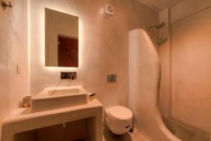 a bathroom with a sink and a toilet and a mirror at The Muses of Santorini Private Jacuzzi Suites in Vóthon