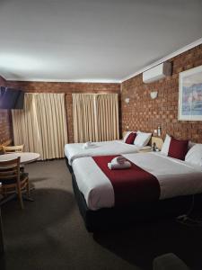 um quarto de hotel com duas camas e uma mesa em Courtyard Motor Inn em Shepparton