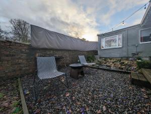 a backyard with two chairs and a table and a wall at The Cabin with optional Hot Tub Projector DEPOSIT REQUIRED FOR PROJECTOR in Bonnybridge