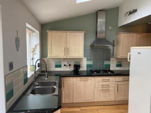 una cocina con armarios de madera y fregadero en HAMS LODGE - - Strictly Only ONE GUEST ALLOWED IN ONE ROOM A SECOND ACCOMPANYING PERSON WILL NOT BE ALLOWED INTO THE PROPERTY, en Birmingham