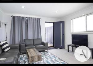 un soggiorno con divano e TV di Modern cottage central location a Phillip