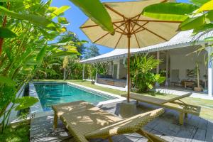 eine Terrasse mit einem Tisch und einem Sonnenschirm neben einem Pool in der Unterkunft Vicolo ArtVillas in Uluwatu