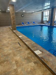 a large swimming pool with blue chairs in a building at Alvina apartment hotel in Tsaghkadzor