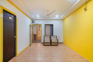 a hallway with two chairs and a yellow wall at FabExpress Luxury Inn in Hyderabad