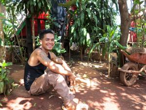 a man squatting on the ground in a garden at Ratanakiri Homestay & Jungle Trek in Banlung