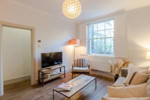 a living room with a couch and a tv at Bright De Beauvoir Pied à Terre in London