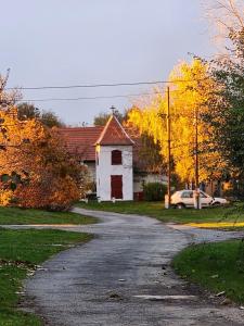 uma pequena igreja branca sentada ao lado de uma estrada em Csendliget Vendégház em Geresdlak
