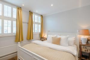 a bedroom with a white bed with yellow curtains at Bright De Beauvoir Pied à Terre in London