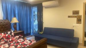 een woonkamer met een bank en blauwe gordijnen bij Grey Orchard Homestay - A Family Place in Lahore