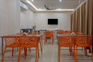 a room with orange chairs and a table and a tv at Treebo Trend Windsor Heights in Ooty