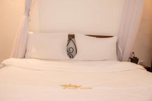 a bed with white sheets and pillows at Harry's Kisumu Oasis in Kisumu