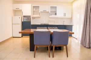 a kitchen with a table and chairs and a refrigerator at Harry's Kisumu Oasis in Kisumu