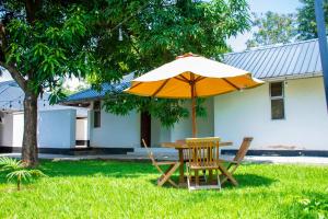 a table and chair with an umbrella in the grass at Harry's Kisumu Oasis in Kisumu