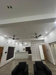 Habitación con 2 sillas y 2 ventiladores de techo. en Tropical oasis en Thiruvananthapuram