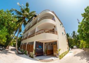 a building on the beach with a palm tree at Manta Sea View Himandhoo in Himandhoo 