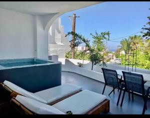 un patio con bañera, sillas y mesa. en The Muses of Santorini Private Jacuzzi Suites en Vóthon