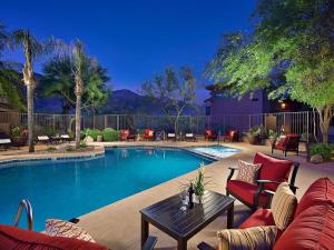 uma piscina com cadeiras vermelhas e uma mesa ao lado em Tucson Vacation Rentals em Tucson