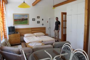 a man standing in a bedroom with a bed and chairs at Penzion Gomelská in Horní Stropnice