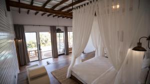 a bedroom with a white canopy bed with a window at Lov Faralya Beach & Nature Retreat in Faralya