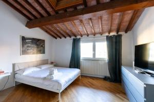 Schlafzimmer mit einem Bett und einem Flachbild-TV in der Unterkunft AFFITTACAMERE I BIMBI in Livorno